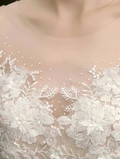 the back of a woman's wedding dress with white flowers on it and pearls