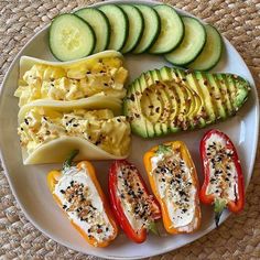 an assortment of vegetables on a plate with cheese and sauces next to sliced cucumbers