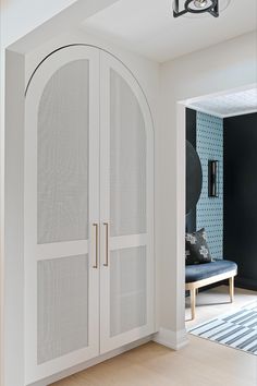 a white closet with two doors and a blue couch in the corner next to it