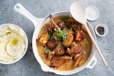 a white bowl filled with meat and mashed potatoes on top of a gray table