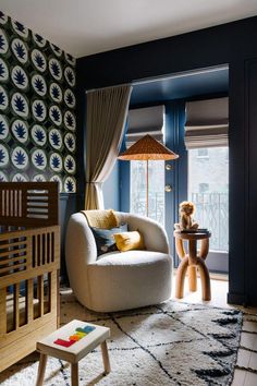 a living room filled with furniture next to a window covered in blue and yellow wallpaper