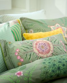 the pillows on the bed are green and have pink flowers, leaves and dots in them