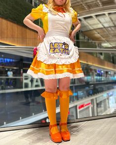 a woman dressed in an orange and white outfit posing for the camera with her hands on her hips