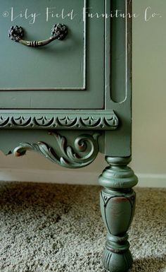 an old dresser painted in green with ornate carvings and knobs on the drawer pulls