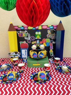 the table is set up with colorful paper decorations and plates, cups, and napkins