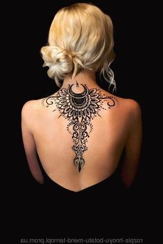 the back of a woman's neck with an intricate tattoo design on her shoulder