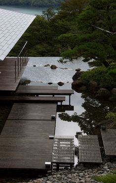 a wooden dock sitting on top of a river next to a lush green forest filled with trees