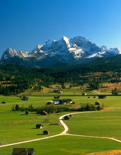 the mountains are covered in snow and green grass, with small houses on either side