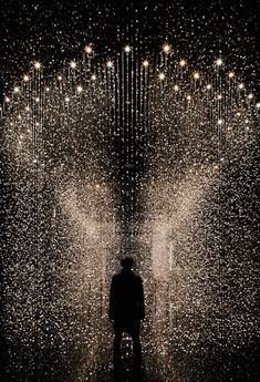 a man standing in the middle of a room filled with lights and raindrops