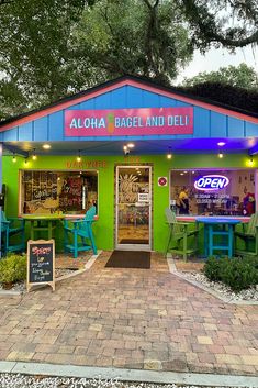 the front entrance to aloha bagel and deli with neon signs on it