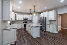 an empty kitchen with white cabinets and wood flooring in the middle, along with stainless steel appliances