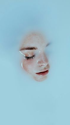 a woman's face is reflected in the water with bubbles on her nose and eyes