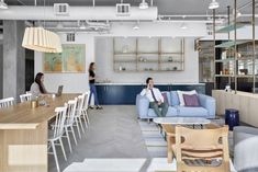 two women are sitting on the couches in an open concept office with blue and white furniture