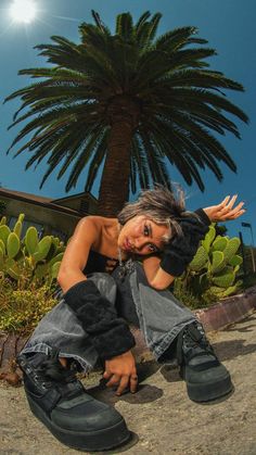 a woman sitting on the ground in front of a palm tree