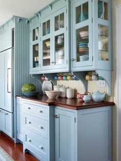 a kitchen filled with lots of blue cabinets and counter top space next to a wooden floor