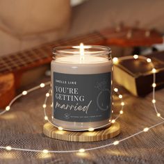 a lit candle sitting on top of a wooden table next to a string of lights