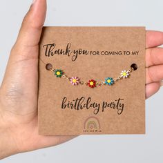 a hand holding up a card with a flower bracelet on it's side that says thank you for coming to my birthday party