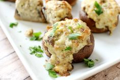 several stuffed mushrooms on a white plate with parsley