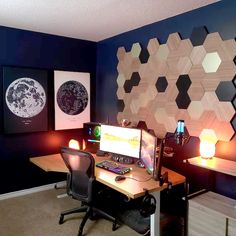 a desk with a computer sitting on top of it in front of a blue wall