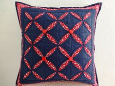 a blue pillow with red and white designs on the front is sitting on a table