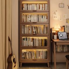 a laptop computer sitting on top of a wooden book shelf next to a desk with a guitar