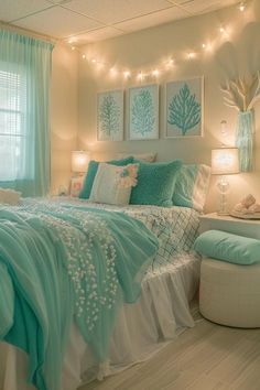 a bedroom decorated in aqua and white with lights strung above the bed, along with pictures on the wall