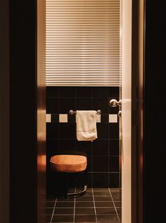 a black tiled bathroom with a wooden stool