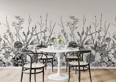 a white table and chairs in front of a wall with flowers painted on the walls