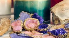 purple and gold crystals on a table next to a candle with a skull in the background