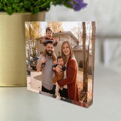 a family photo is displayed on a table next to a potted plant