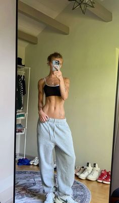 a woman taking a selfie in the mirror with her cell phone while wearing sweatpants