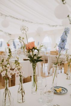 several vases filled with flowers sitting on top of a white tablecloth covered table