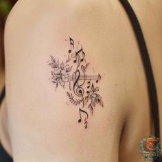 a woman's back shoulder with music notes and flowers on the left side of her body