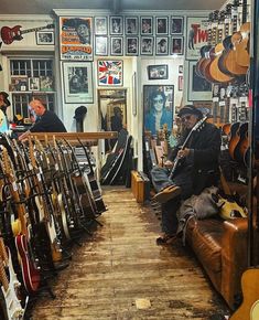 a man sitting on a couch in a room filled with guitars