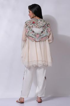 Ivory white floral embroidered jacket. Paired with an inner and embroidered pant.
Components: 3
Pattern: Embroidered
Type Of Work: Chikankari
Neckline: V Neck
Sleeve Type: Flared
Fabric: 25% Silk, 75% Cotton
Color: Ivory,White
Other Details: 
Attached cotton lining
Model Height: 5 ft 7 inches, wearing size M
Closure: Zip
Occasion: Resort - Aza Fashions Embroidered Off White Georgette Sets, Off White Embroidered Georgette Sets, White Georgette Sets With Pearl Embroidery, White Outerwear With Floral Embroidery For Wedding, Wedding White Outerwear With Floral Embroidery, Spring Embroidered Georgette Sets, White Embroidered Long Sleeve Sets, Spring Off White Sets With Embroidered Border, Cream Georgette Sets With Floral Embroidery