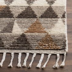 an area rug with fringes on top of it and a wooden floor in the background