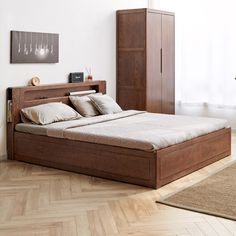 a large bed sitting on top of a hard wood floor next to a tall cabinet