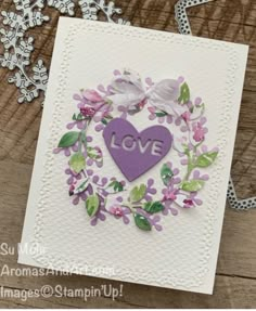 a close up of a card on a wooden table with flowers and leaves around it