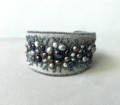 Bead embroidery cuff bracelet, freshwater pearl cuff Winter lace, statement beacelet,  bead embroidered bracelet, statement jewelry 62 pearls! This statement bracelet is stitched on light grey felt, I used freshwater pearls of different tones of greys - silver, gunmetal, silver peacock blues and greens, creams and whites as well. Some are big, some are the tiniest, some are smooth, some are rustic. They are embraced by tiny silver lined light grey rainbow seed beads. Bracelet is neatly backed with light grey Ultrasuede. The bracelet has beautiful curved shape, it is wider at front and more narrow at the ends. The width of the front part about 1 1/2 inches (3,9 cm). The inside diameter of this bracelet is about 2 1/2 inches (6,4 cm) but it can be adjusted bigger or smaller by slowly bending Handmade Adjustable Luxury Pearl Bracelet, Elegant Beaded Cuff Bracelets, Elegant Adjustable Decorative Bracelets, Luxury Beaded Pearl Bracelet For Wedding, Elegant Beaded Cuff Bracelet, Elegant Handmade Cuff Bracelet, Elegant Beaded Cuff Jewelry, Luxury Handmade Pearl Wedding Bracelet, Handmade Luxury Pearl Bracelet For Wedding