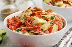 two white bowls filled with cucumber and tomato salad on top of a table