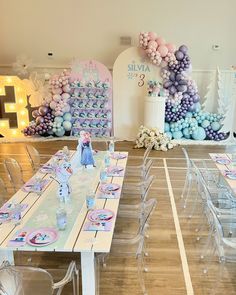 a table set up for a birthday party with balloons and decorations