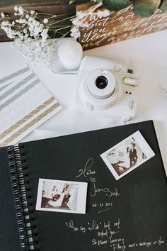 a camera and some pictures are on a table next to a notepad with writing