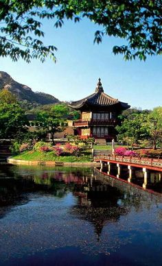 a bridge over a body of water in front of a building with flowers on it