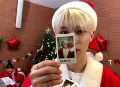 a man in a santa hat holding up a polaroid