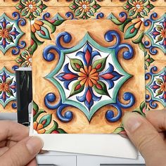 two hands are holding up some colorful tiles