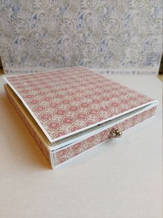 a pink and white box sitting on top of a table next to a wall paper