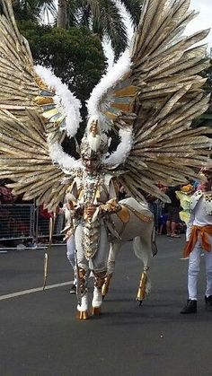 a man riding on the back of a white horse down a street next to tall palm trees