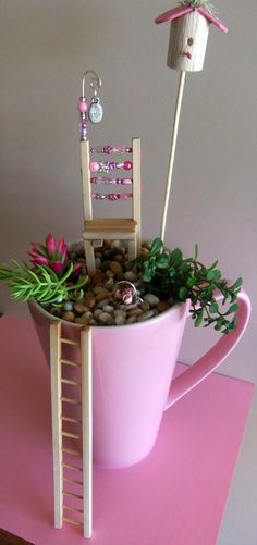 there is a pink cup with rocks and plants in it