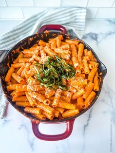 a red skillet filled with pasta and topped with parmesan cheese