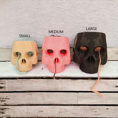 three different colored masks sitting on top of a wooden table next to each other with words written below them